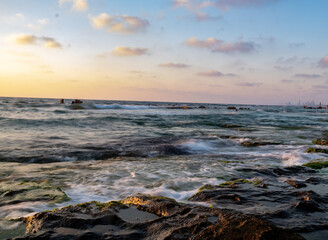Naklejka premium water splash on rocks sunset over the sea