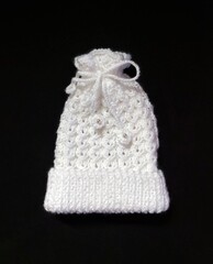 Hand knitted hat for newborn baby, in white color.