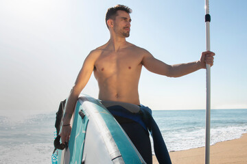handsome guy and athlete with surfboard on the beach
