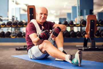 Fototapeta na wymiar A portrait of senior man having a rest after exercise in the gym. People, healthcare and lifestyle concept