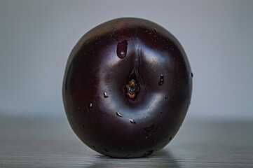 blue plum with a drop of water on a white background close-up