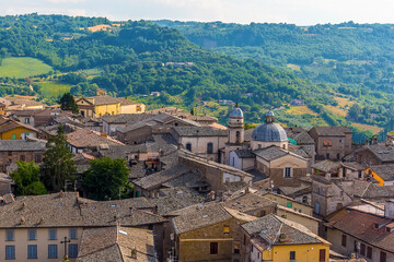 Fototapeta na wymiar A jumble of roof tops rise above the surrounding countryside in Orvieto, Italy in summer