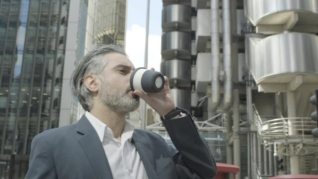 Corporate business man commuting to work drinking coffee from reusable recycled cup in the city of London