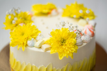 Cake with yellow stains, yellow chrysanthemums and meringue