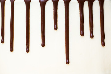 Chocolate drips on the background of white cream