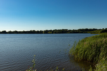 View of the lake from the green shore on a bright sunny day