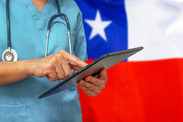Surgeon or doctor using a digital tablet on the background of the Chile flag.