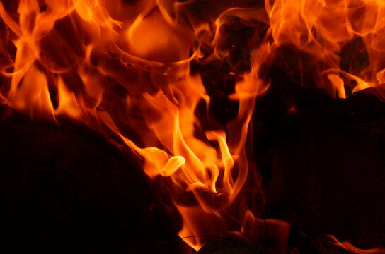 Texture of orange and red flames from a wood fire outdoors, template for graphic use of flames or fire, wallpaper and fire background isolated on black background