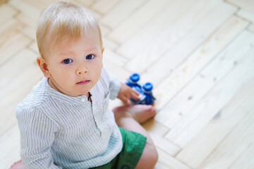 Baby boy sitting on floor and holding toy car