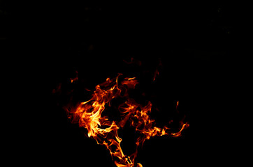 Texture of orange and red flames from a wood fire outdoors, template for graphic use of flames or fire, wallpaper and fire background isolated on black background