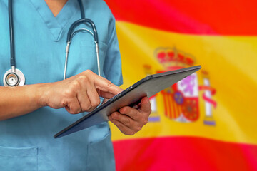 Surgeon or doctor using a digital tablet on the background of the Spain flag.