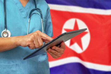 Surgeon or doctor using a digital tablet on the background of the North Korea flag.