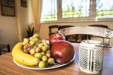 Plate with fruits (apples, banana) on the wooden table.
