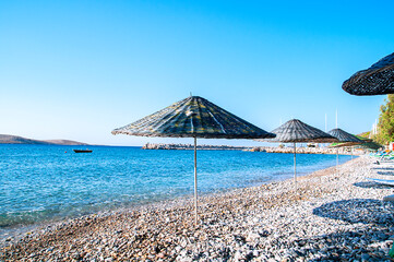 Sunshades made of natural materials, placed at the seaside.