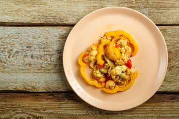 Vegetable stew on a beige plate on a wooden table copy space