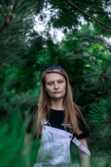 Portrait of a young blonde girl near pine needles
