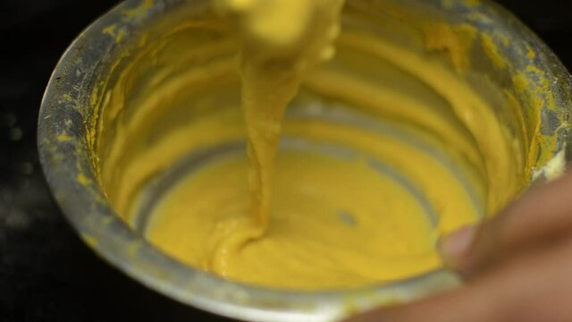A lady is mixing gram flour in water for food preparation