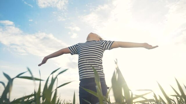 boy prays pulls hands to the sky against a blue sky. child concept faith religion and happy family. kid son hands to the side against the blue sky jew praying to god. worship and gratitude lifestyle