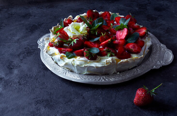 Homemade meringue cake Pavlova with straeberries and mint on the dark background. Copy space