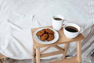 Breakfast in bed. Hot coffee with oatmeal cookies with chocolate on a wooden tray.