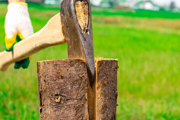 The wood chopper sticks out in wooden hemp. Ax and ax handle. Man's , male hands in white colors gloves holding an axe.