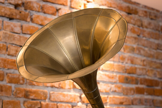 Golden gramophon tube. Against the background of red bricks.