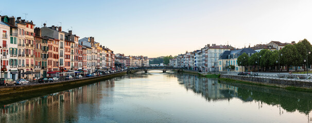 Panoramic view of Bayonne and the Nive River at sunrise in the French Basque Country, France. Old colorful facades and their reflection on the water surface.