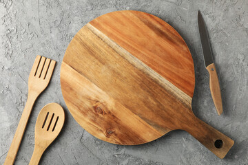 Cutting board and kitchen cutlery on gray background