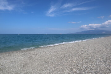 Beach on a summer day, blue sea and sky with white clouds, vacation at the sea, Calabria, Italy