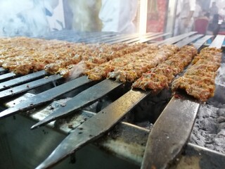 Cooking Adana kebabs on the restaurant style grill