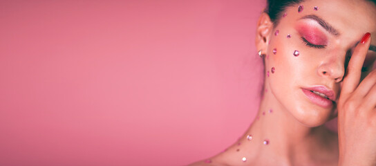 Girl with pink make-up and rhinestones on her face  on a pink background