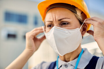 Fototapeta na wymiar Female civil engineer putting on protective face mask during coronavirus epidemic.