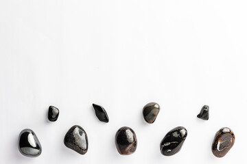 Obraz na płótnie Canvas Black semi-precious stones arranged neatly with a empty space above them on a white background