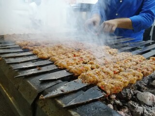 Cooking Adana kebabs on the restaurant style grill