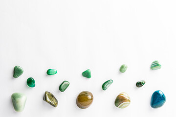 Green semi-precious stones arranged neatly with a empty space above them on a white background