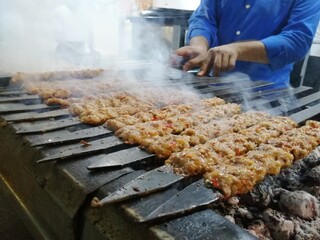 Cooking Adana kebabs on the restaurant style grill