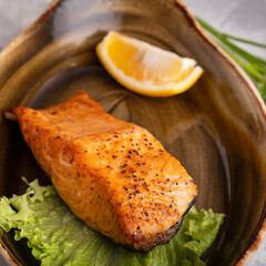 Closeup photo of grilled salmon fillet served with lemon. Diet and healthy food