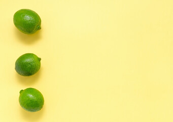 Fresh juicy limes on a yellow uniform background. Citrus Vitamin C Healthy Eating and Lifestyle