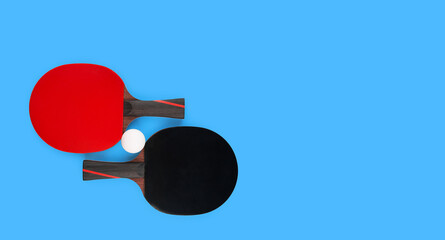 two tennis rackets with a ball on a blue table