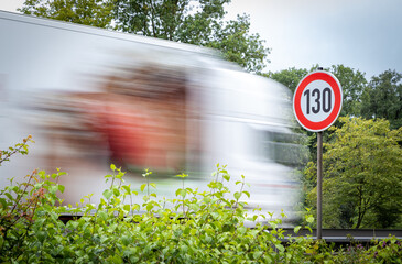 Schild mit der Geschwindigkeitsbegrenzung Tempo 130 auf einer deutschen Autobahn, dahinter ein LKW...