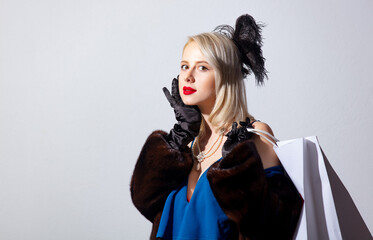 Blonde woman in vintage blue dress and fur coat with shopping bags