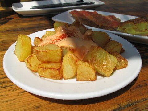 A plate of patatas bravas - Spanish dish: fried potatoes cut into cubes with spicy tomato sauce