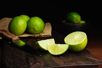 Fresh, raw and organic sliced green lemon in focus with other lemons in composition