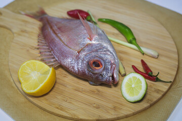 fresh pink fish is lying on a wooden Board next to a sliced lemon