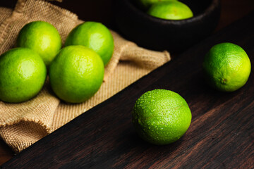 Fresh, raw and organic green lemon in focus with other lemons in composition