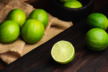 Fresh, raw and organic sliced green lemon in focus with other lemons in composition
