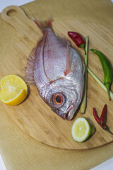 fresh pink fish is lying on a wooden Board next to a sliced lemon