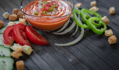 Tomato or gazpacho soup in glass on dark wood