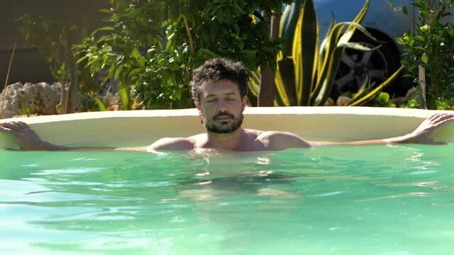 Caucasian man swims and relaxes in the pool