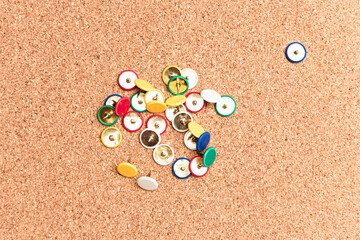Flat lay view of multi colored thumb tack over a cork board